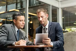 Two businessmen wearing suit having a business meeting