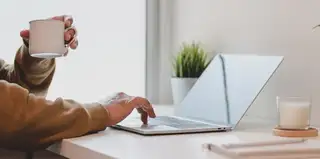 A hand using a laptop on desk
