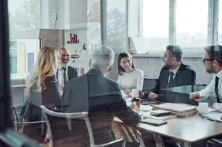 group of co-workers sat around a table in a meeting